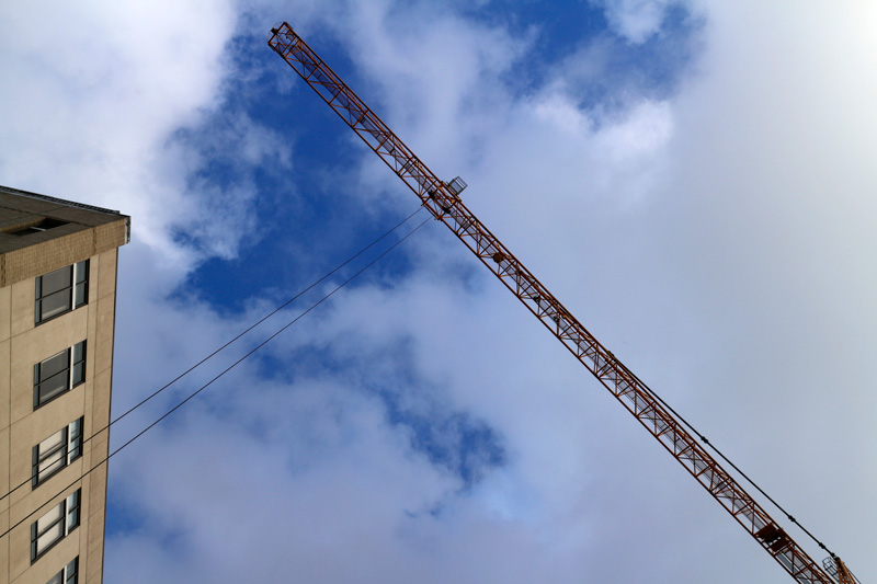 Photo of a construction crane reaching skyward near a building at a disorienting angle